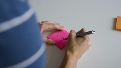 el profesional corporativo dibuja un diagrama y un boceto para el diseño de un nuevo producto en una nota adhesiva rosa
