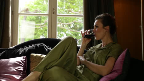 beautiful adult woman relaxing in sofa with glass of red wine