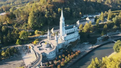 aerial tilting establishing shot of the lourdes cathedral with tourists outside