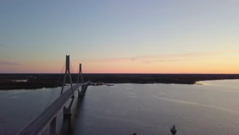 Aerial,-tracking-shot-flying-over-the-iconic-Raippaluodon-silta,-Replot-bridge-at-sunset-in-the-Kvarken-archipelago,-Finland's-longest-bridge-located-in-Ostrobothnia,-Finland-on-a-sunny-summer-evening