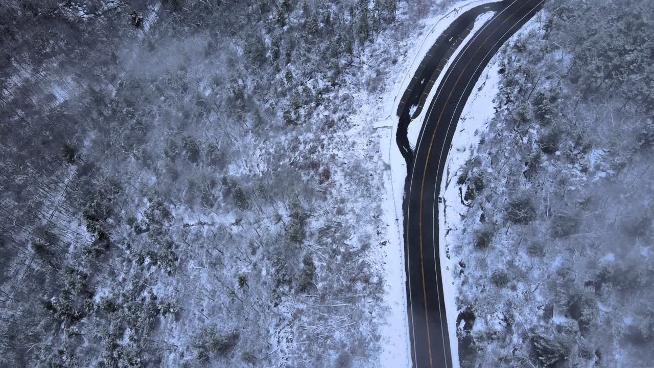 구름이 낀 겨울날 경치 좋은 고속도로가 있는 산골짜기의 눈 덮인 산과 숲 위로 구름을 날고 있다