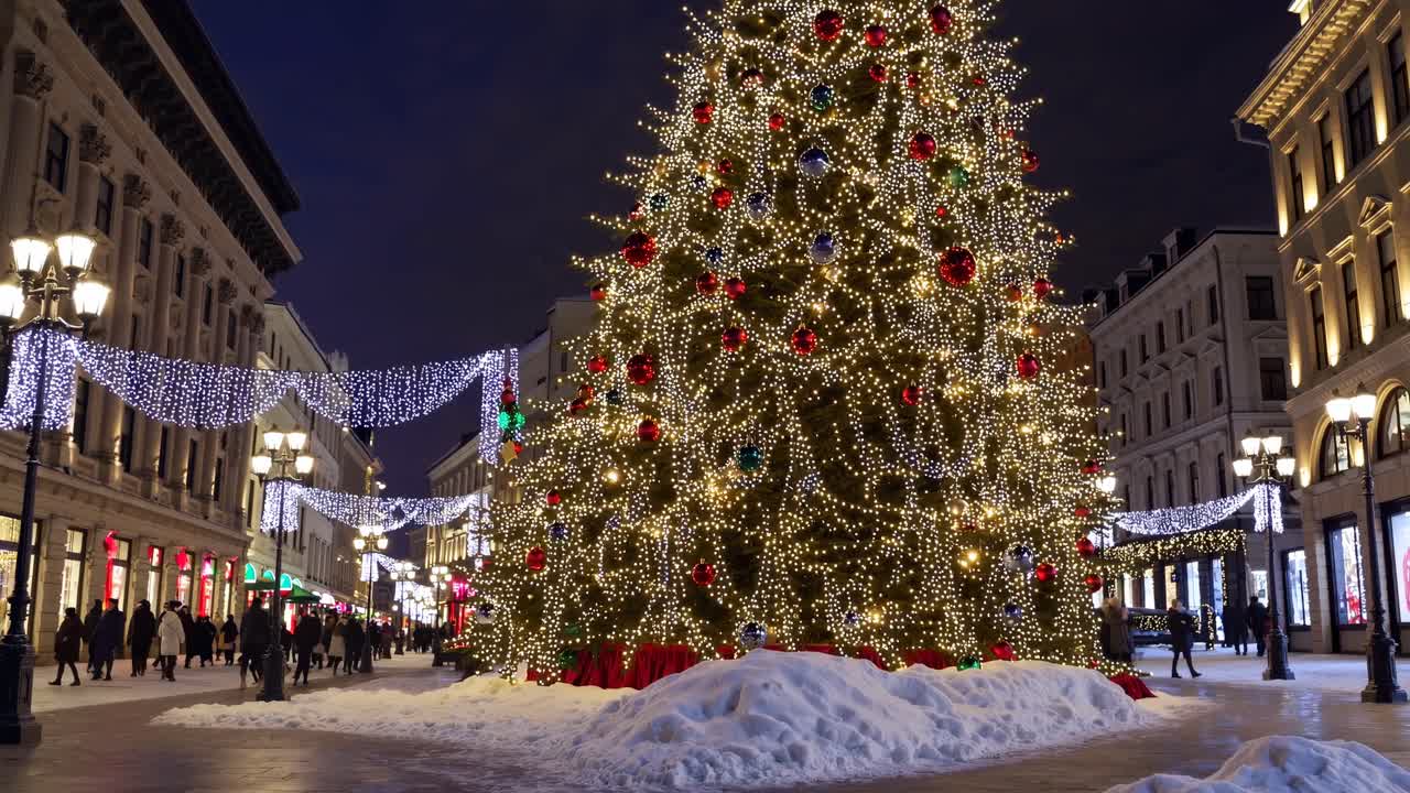 Festive city street at night with a towering Christmas tree, captured from a low angle