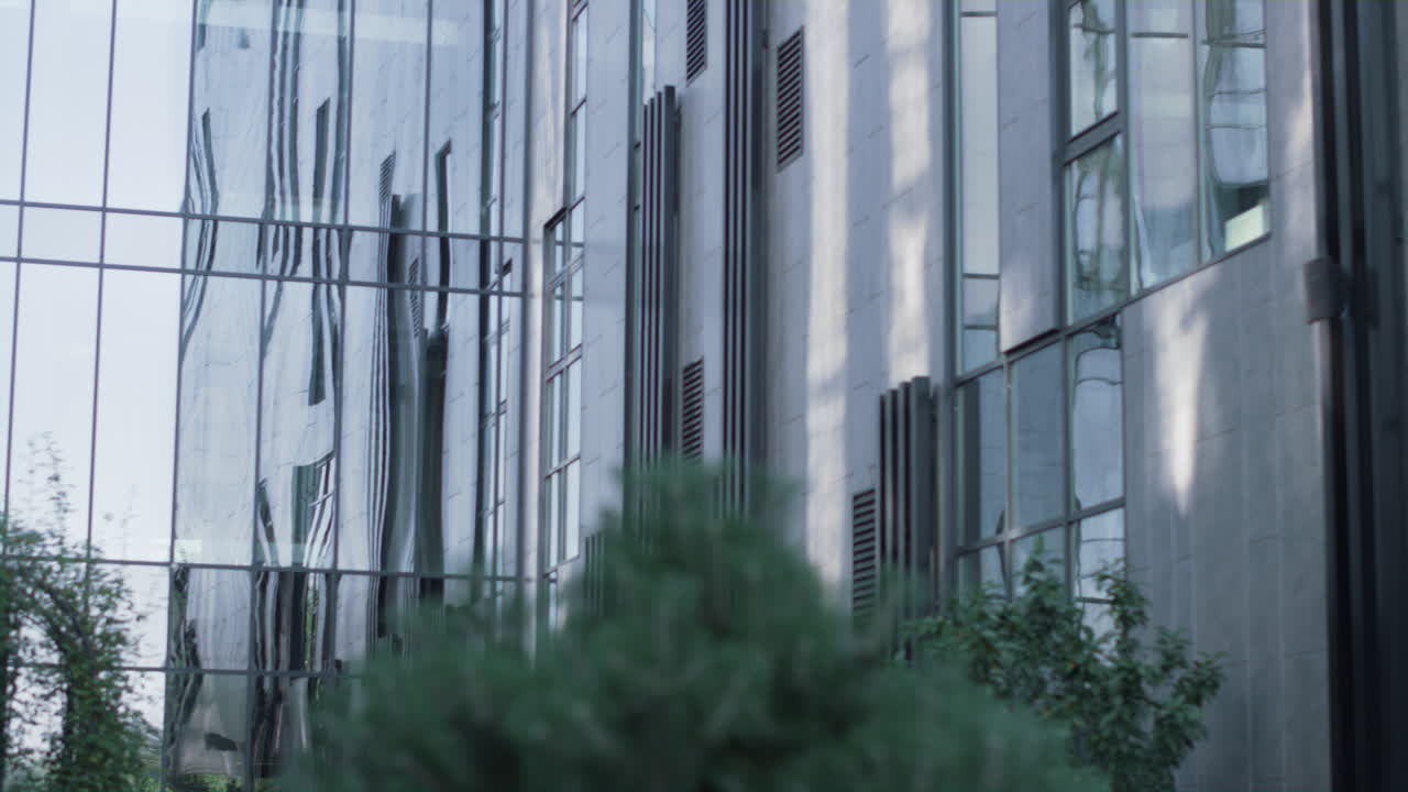 Exterior de moderno edifício de escritórios de vidro. Janelas refletindo o céu e um carro passando
