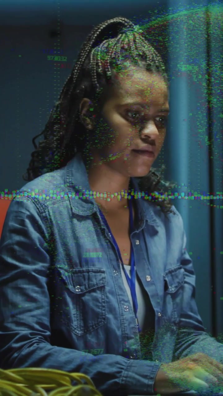 Vertical video: Glitching, tech in denim fixing at control room, typing on keyboard, yellow cable