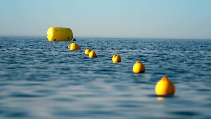 Protective floats on the rope on the beach in the water, selective focus