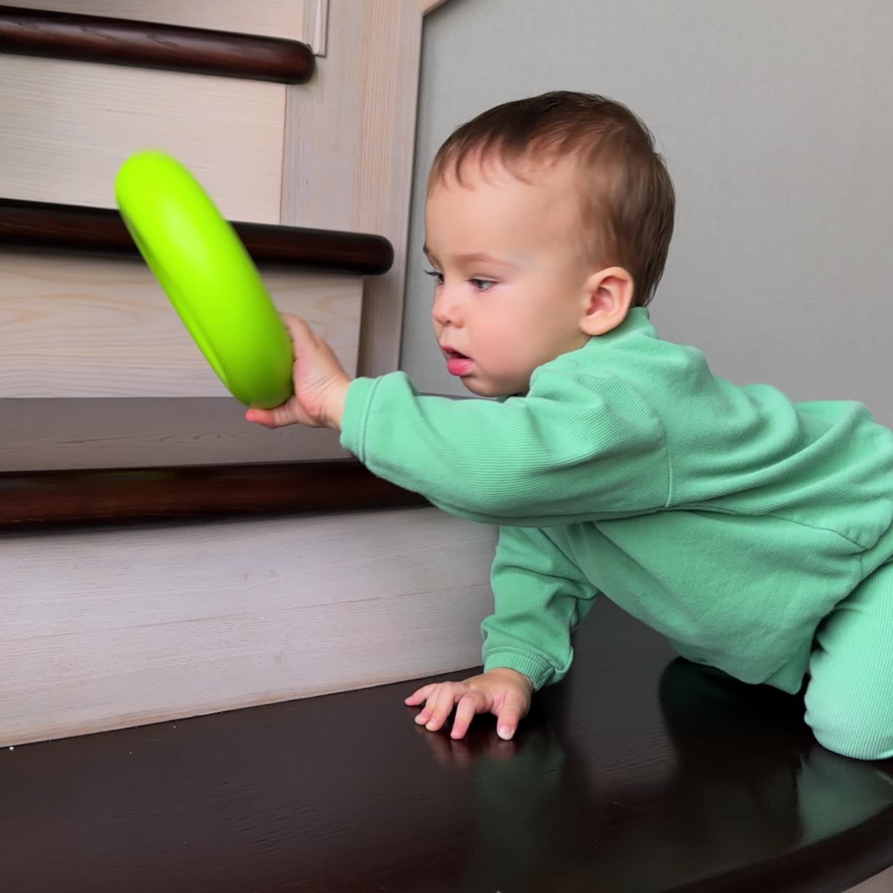 Lovely little boy throws the toy and follows it on the stairs. Beautiful child climbs the step and sneezes twice