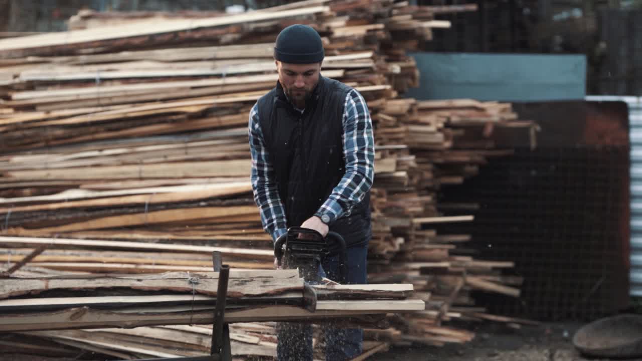 retrato de un trabajador cortando trozos de madera con una motosierra