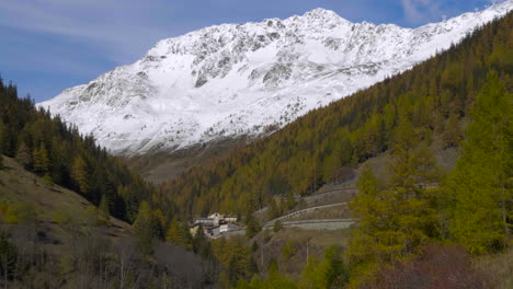 a tilting up view of a scenic landscape snow-capped mountains and a village centered in the valley covered by forest