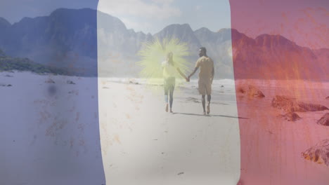 animación de la bandera de francia y fuegos artificiales sobre una feliz pareja biracial caminando por la playa