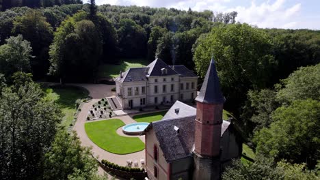 aerial view above trees, skimming a bell tower, approaching a beautiful southern france castle with smoking chimney