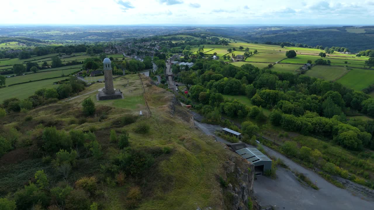 Scenic drone footage of Crick Memorial Tower overlooking rolling hills and farmland in the Derbyshire Dales, England, on a sunny day