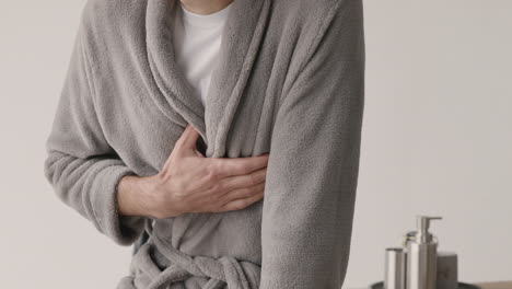 Nahaufnahme-Eines-Nicht-Erkennbaren-Mannes-In-Schlafanzug-Und-Robe,-Der-Zu-Hause-Schmerzen-In-Der-Brust-Hat-Und-Morgens-Zu-Hause-Seinen-Herzbereich-Berührt