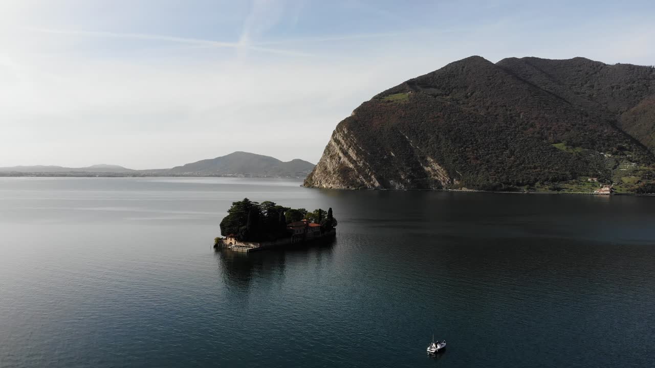drone flies around San Paolo island on Iseo lake during a sunny autumn day