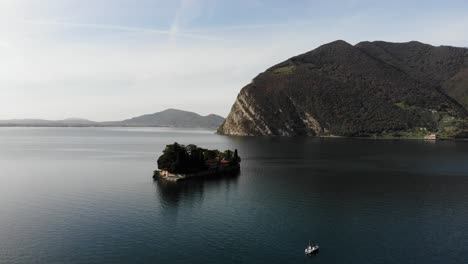 drone vuela alrededor de la isla de san paolo en el lago iseo durante un soleado día de otoño