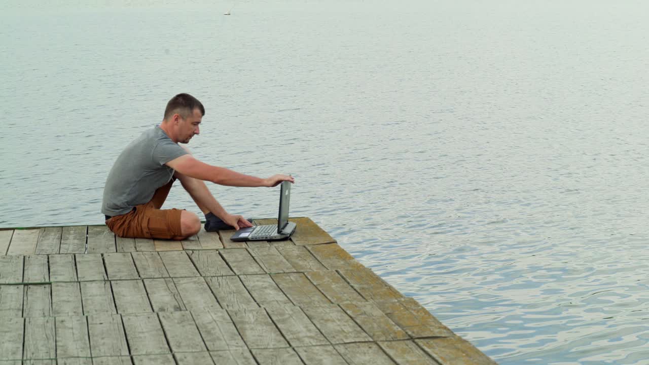 Man on the pier working on a laptop