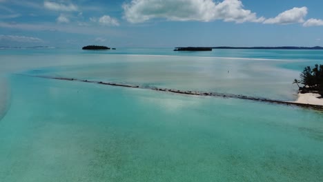 lone-person-on-remote-tropical-lagoon-with-small-islands-and-palm-trees-aerial-shot