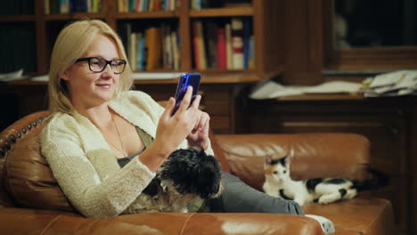 a woman uses a smartphone in the home library next to her her pets