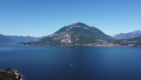 aerial wide shot showing beautiful blue colored lake como with mountains in background against blue sky