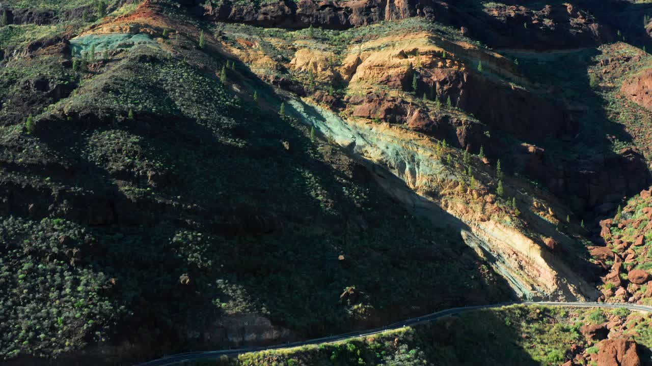 Aerial orbit ascend of Los Azulejos de Veneguera, Mogan, capturing vibrant layered rocks in Gran Canaria, Spain