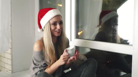 friends relaxing at home. young woman relaxing with cup of tea at home sitting on the window sill
