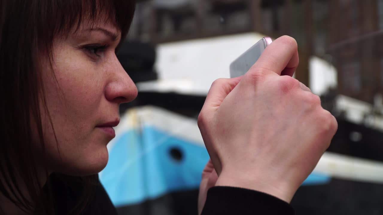 암스테르담의 운하를 가로질러 배를 타고 전화로 사진을 찍는 소녀