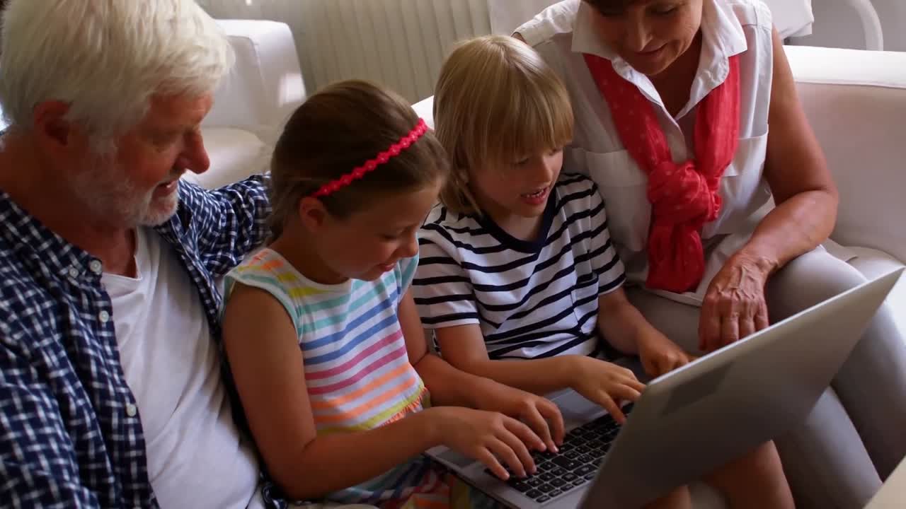 Grandchildren using laptop with their grandparents