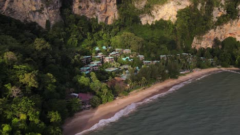 toma aérea de drones en movimiento hacia adelante de un hermoso complejo rodeado de bosques tropicales a lo largo de la playa de raily en krabi, tailandia durante el día