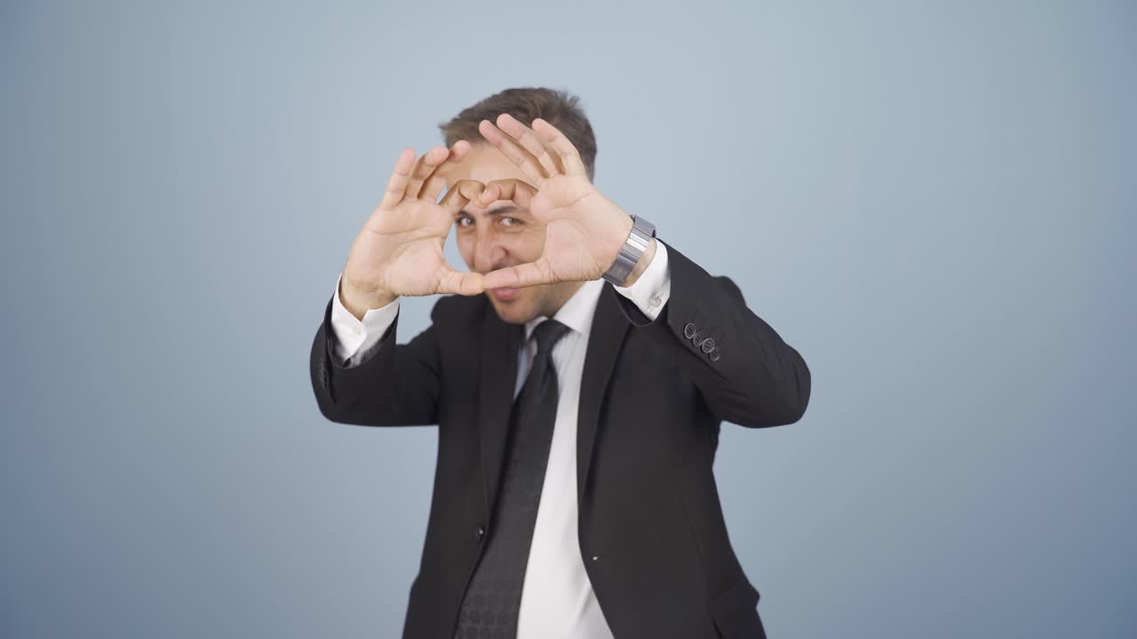 비즈니스맨이 카메라 앞에서 심장을 짓고 있습니다.