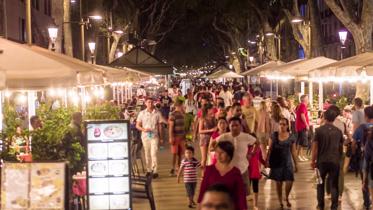 escena nocturna en una calle de la ciudad con personas comiendo al aire libre