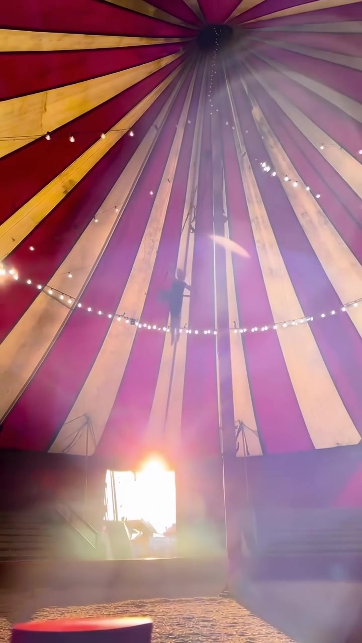 Acrobata se apresentando no trapézio dentro de uma tenda de circo vibrante