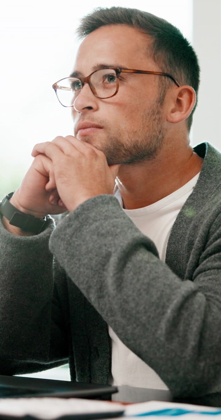 Thoughtful Man Working on Laptop in Modern Office