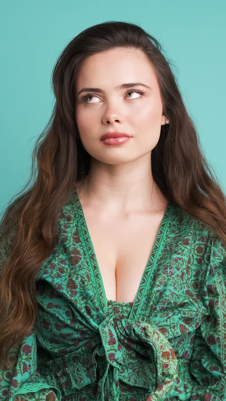 Serious young woman thinking in blue studio