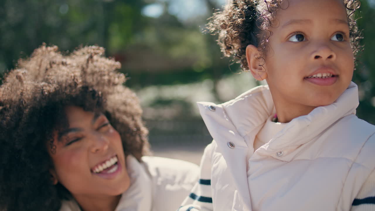 Mãe e filho felizes rindo, passando o fim de semana juntos em um parque ensolarado, em close-up.