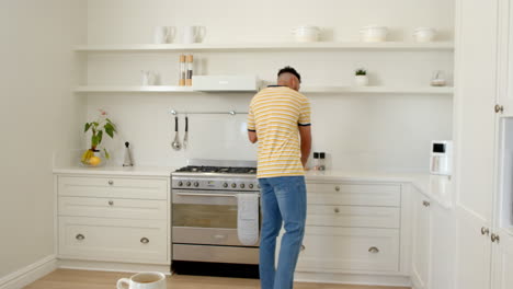 smiling man in kitchen talking on smartphone, enjoying conversation at home, copy space