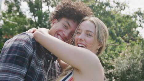 retrato de una feliz pareja diversa abrazándose en el jardín en un día soleado.