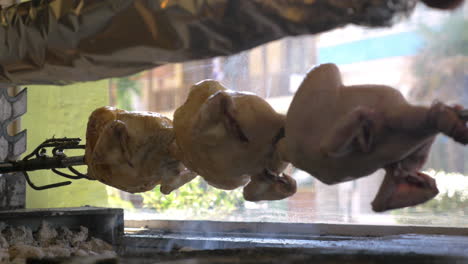 grill chicken rotating on a skewer in cafe against viewing window