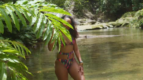 una chica de pie en un río con un bikini en un día soleado