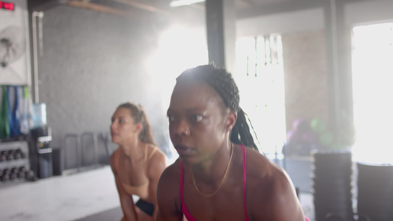 Lifting kettlebells, women exercising in gym, focusing on strength training