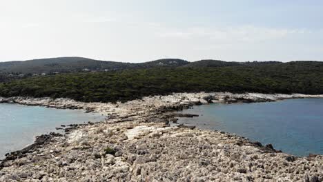 paralia emplisi stony beach overlooking the lush greenery hills in greece- forward aerial