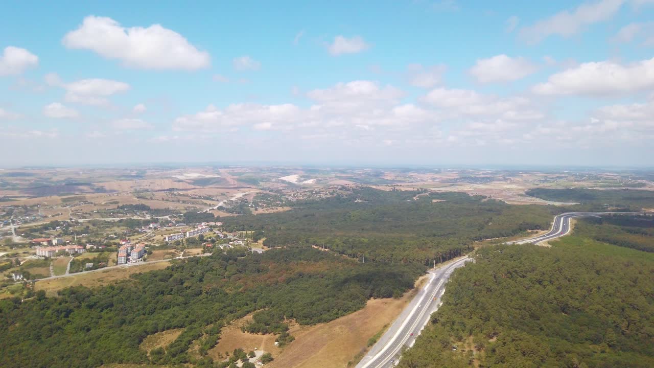 Daytime, a view from the airplane window captures Istanbul city's buildings, forests, and a winding highway partly cloudy sky, moments before landing at Istanbul Airport