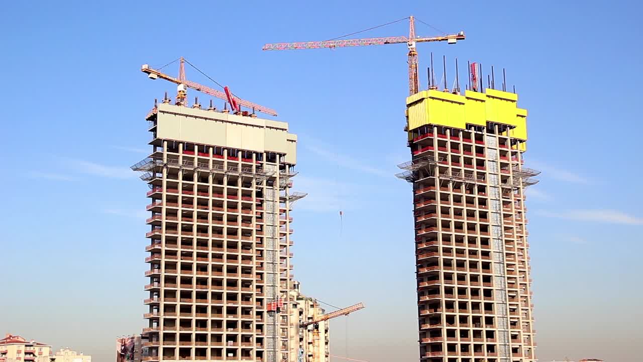 un edificio de la ciudad está siendo hecho por dos enormes grúas de construcción blancas
