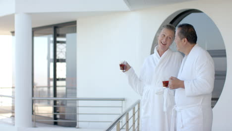 senior couple in bathrobes enjoying coffee on balcony during vacation, copy space