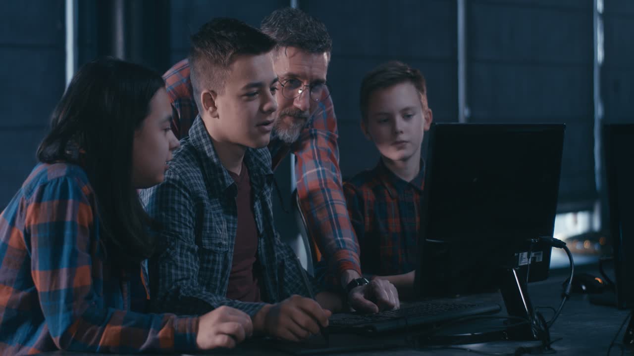 Teenagers learning computer graphic design from a teacher