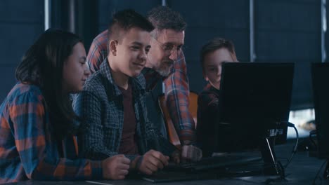 Teenagers learning computer graphic design from a teacher