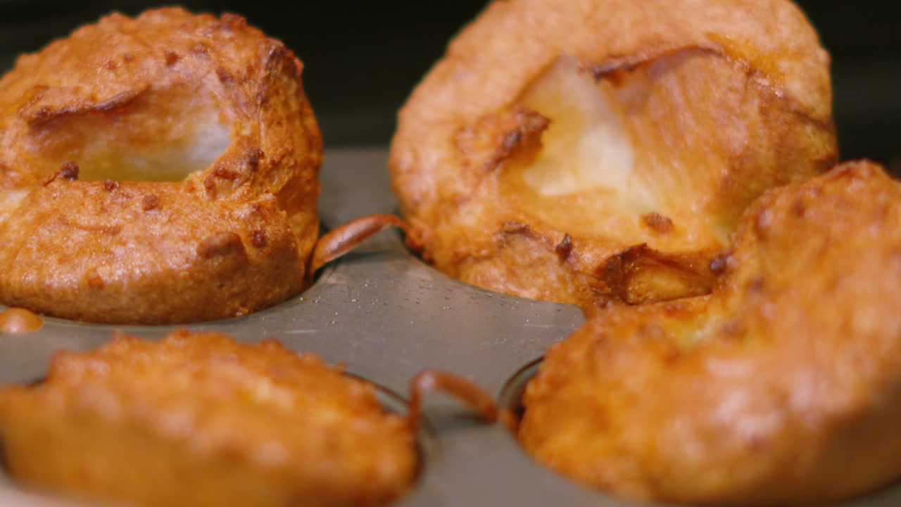 Yorkshire Pudding dalla consistenza croccante e dorata, con distorsione del calore da un ambiente di cucina calda. Perfetto per spot pubblicitari di cibo di alta gamma, promozioni di arrosto domenicale britannico e titoli di ricette irresistibili.