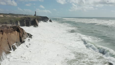 Flying-past-rocky-coastline-with-white-waves-slamming-onto-cliffs