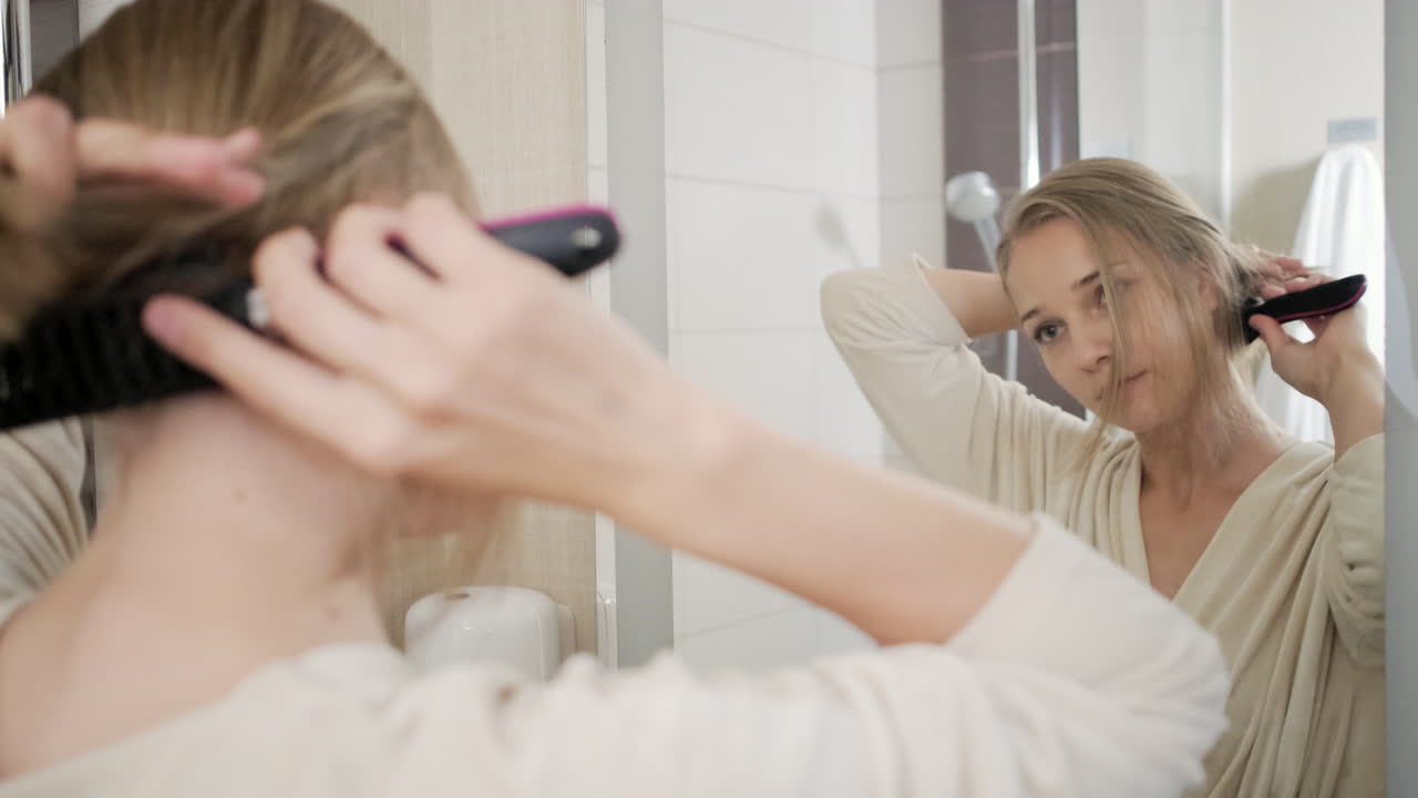 Mujer peinándose el cabello en el baño