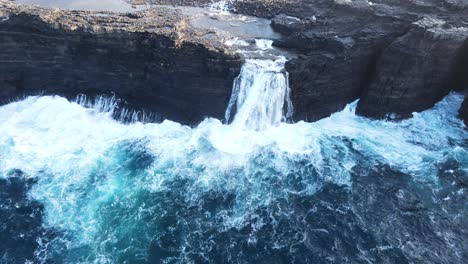 wide approaching drone footage of the bøsdalafossur waterfall near the leitisvatn lake, aka the floating lake, on the vagar island in the faroe islands