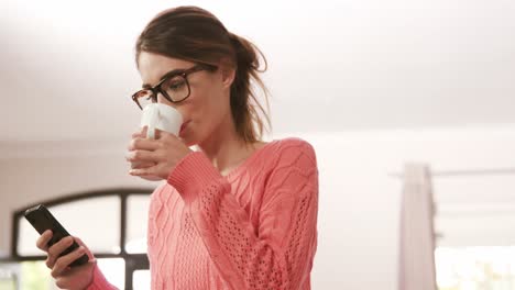 bonita morena usando un teléfono inteligente mientras bebe café
