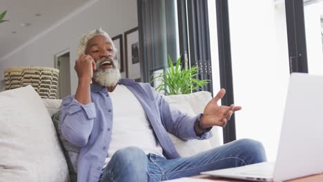 Video-of-african-american-senior-man-using-smartphone-and-laptop